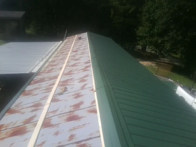 Old rusted panels beside newly installed green metal roofing — Wind Damage Roof Repair by Roofing Brothers in Hersey