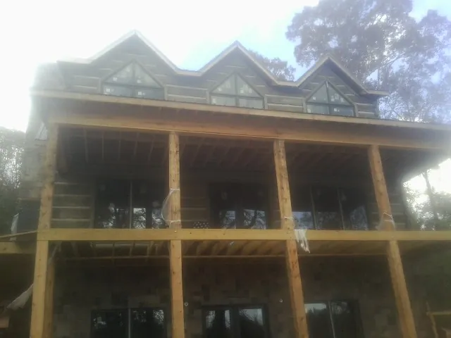 Dormers and porch framing on a large log home under construction — Roof Coating work by our crew in Hersey