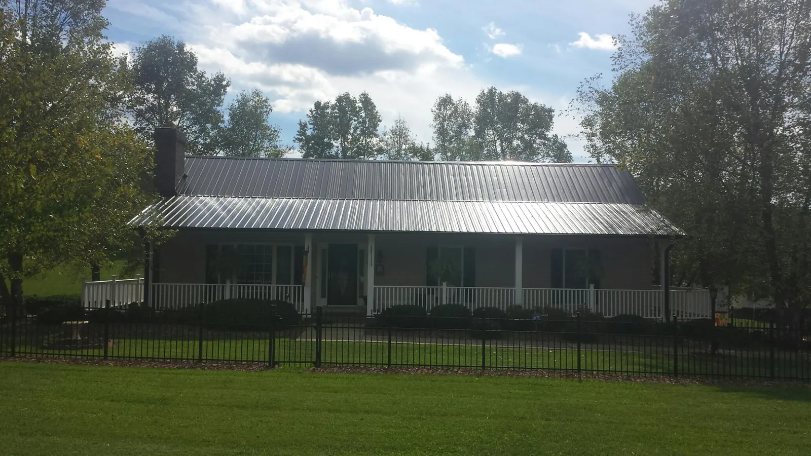 Gray metal roof on a brick ranch with a full width front porch — Gutter Guard Installation work by our crew in Hersey
