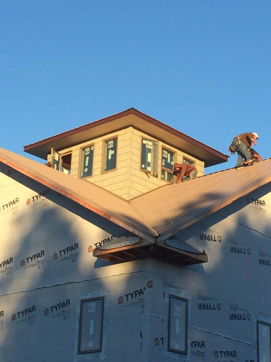 Roofers working around a rooftop cupola on a new metal roof at sunset — Roof Waterproofing in Hersey by Roofing Brothers